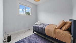 Una camera da letto con un letto, una finestra, un termosifone e una lampada a sospensione.
