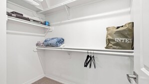 A walk-in closet with shelves, a hanging rod, and a door. - New Build 2-Story Townhome/Single Master Suite (Houston)