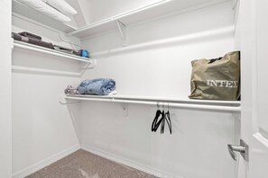 A walk-in closet with shelves, a hanging rod, and a door. - New Build 2-Story Townhome/Single Master Suite (Houston)