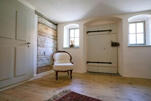 A room with a wooden floor, a white door with a latch, a chair, and a window with a view. - Historic Upper Lusatian timber-framed house (Kottmar)