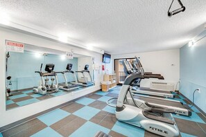 Ein Fitnessstudio mit Laufbändern, Crosstrainern und einer Spiegelwand.