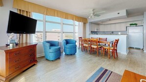 Ein modernes Wohnzimmer mit Flachbildfernseher, einer Holzkommode und einem Essbereich mit Holztischen und -stühlen.