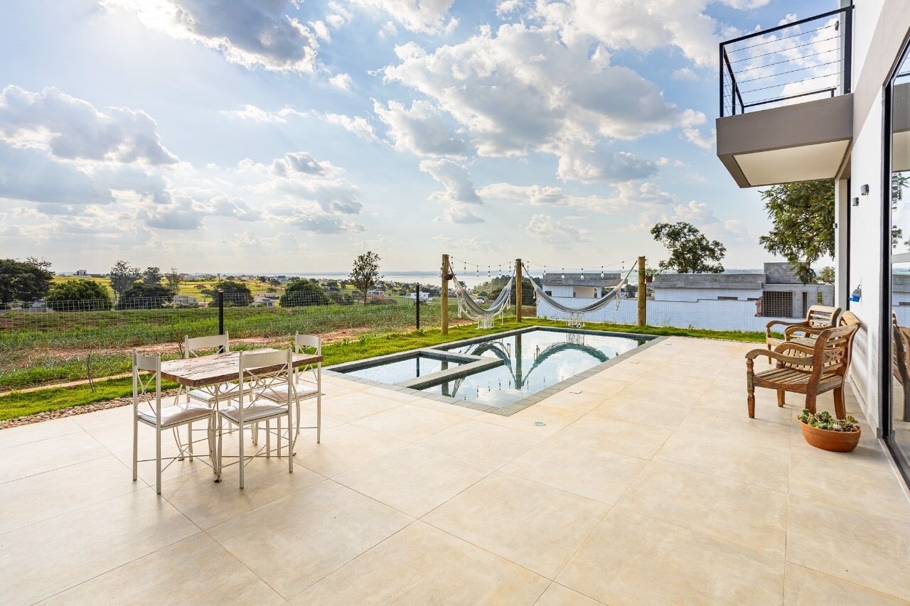 A modern outdoor patio with a pool, seating, and a view of the countryside.