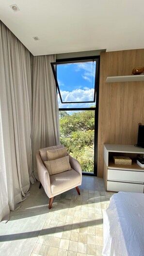 Un dormitorio moderno con un ventanal grande, un sofá, un mueble para TV y una cama.