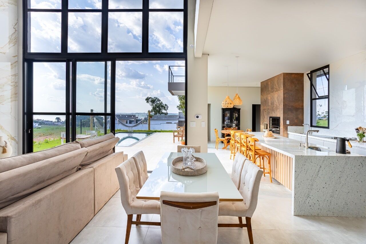 Una cucina moderna con una grande isola, zona pranzo con tavolo in vetro e vista all'esterno.