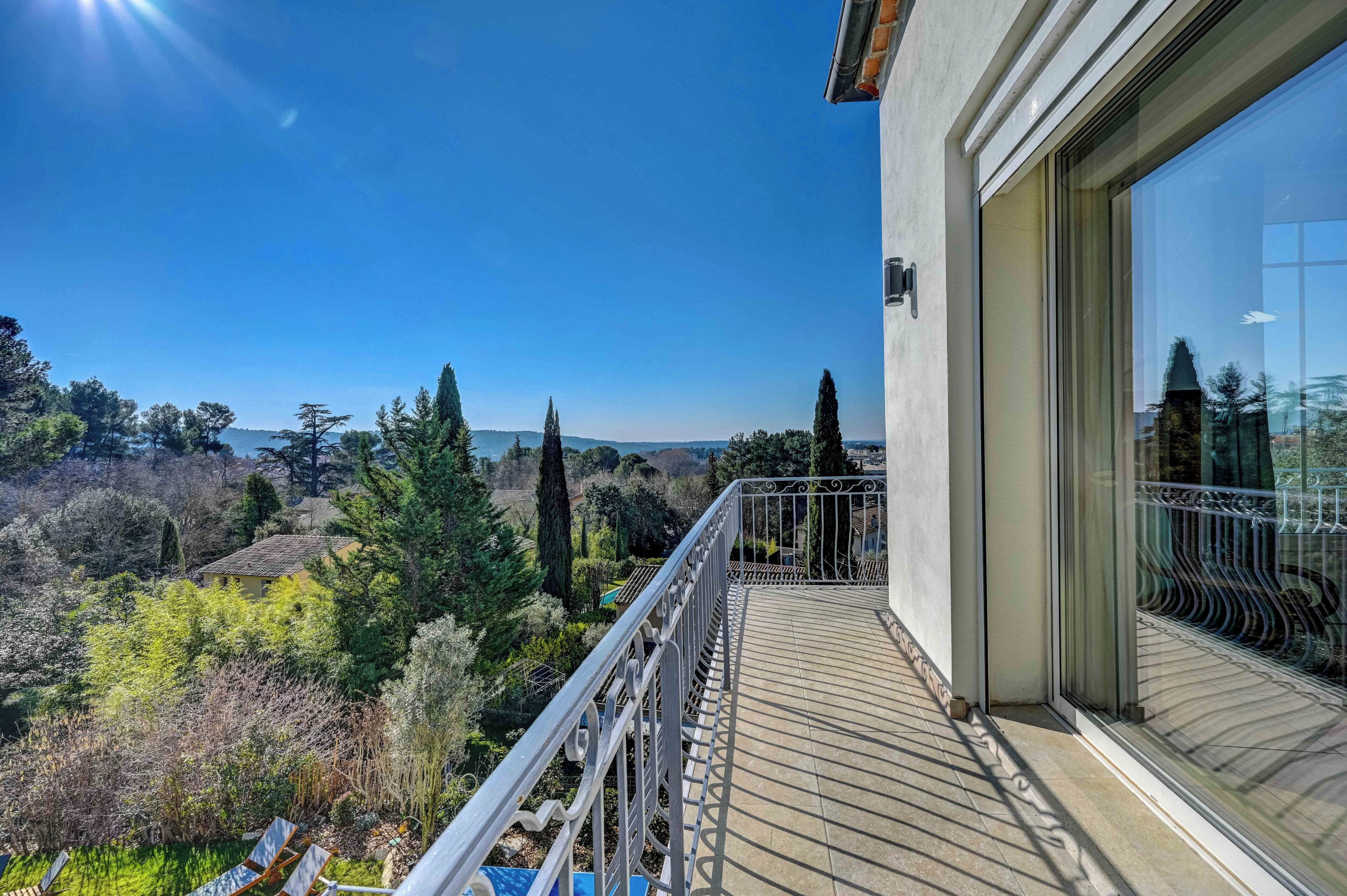 A balcony with a view of a hilly landscape and trees.