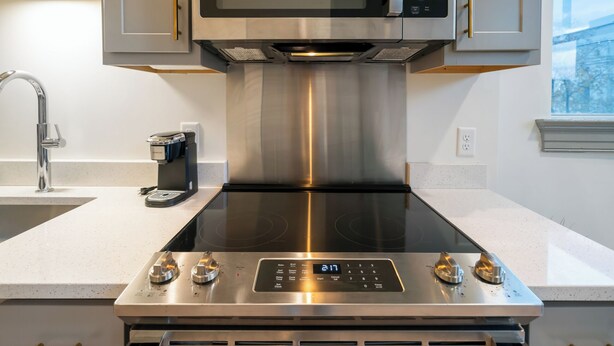 Una cocina con estufa de acero inoxidable, microondas integrado y cafetera.