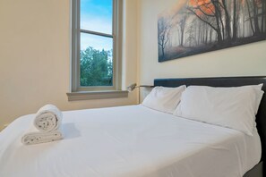 A hotel room with a bed, a window, and a painting on the wall. - Modern Studio - Nearby Parking - Downtown - 3F (Louisville)