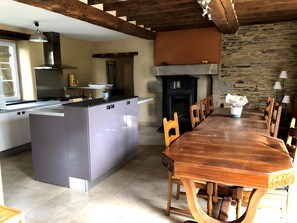 Una cocina moderna con una isla central, una mesa de comedor con sillas y una chimenea de piedra.