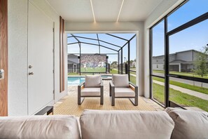 Ein modernes Wohnzimmer mit Blick auf einen Pool, zwei Stühle und ein großes Fenster.