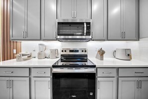 A modern kitchen with grey cabinets, a stainless steel microwave, a built-in oven, and a black dishwasher. - 8BR house sleeps 22 with spa in kissimmee (Kissimmee)