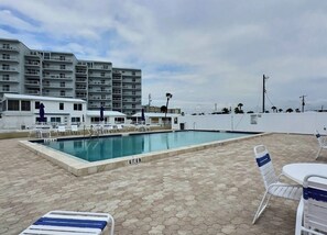 Piscina com espreguiçadeiras e vista para edifícios altos.