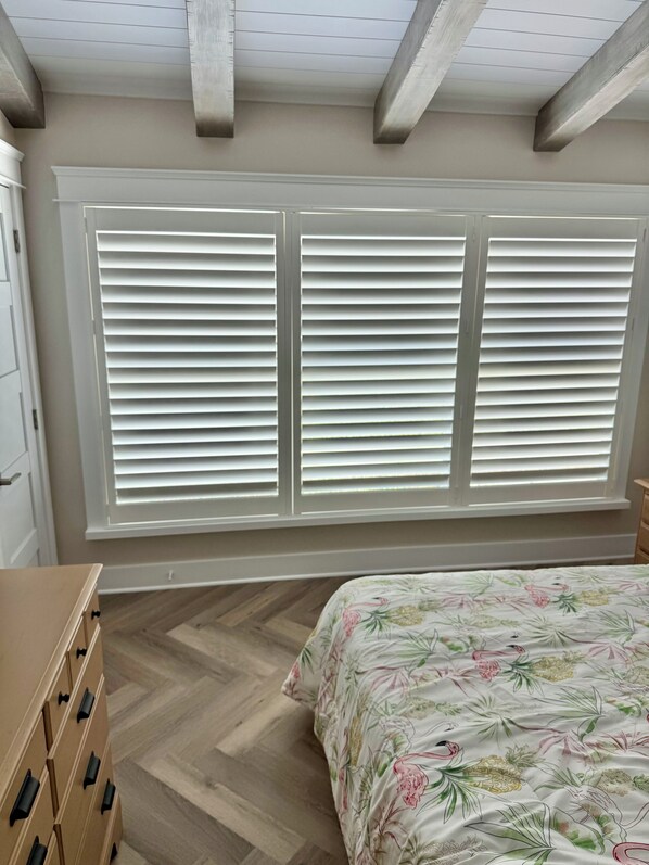 Quarto com uma cama, cômoda e janela com persianas.