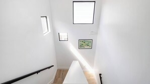 A staircase with a handrail, wooden flooring, and framed pictures on the walls. - Gated 2BR | Modern Austin Home | Near DT | EV Plug (Austin)