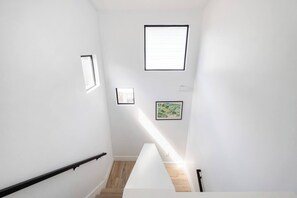 Eine Treppe mit Handlauf, Holzboden und gerahmten Bildern an den Wänden.