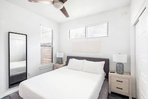A bedroom with a bed, two bedside tables with lamps, a ceiling fan, and a large mirror. - Gated 2BR | Modern Austin Home | Near DT | EV Plug (Austin)