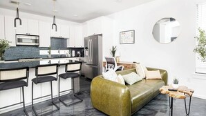 A modern kitchen with white cabinets, a stainless steel refrigerator, and a bar area with stools. - Gated 2BR | Modern Austin Home | Near DT | EV Plug (Austin)