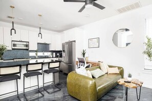 Eine moderne Küche mit weißen Schränken, einem Edelstahlkühlschrank und einer Bar mit Hockern.