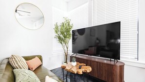 A modern living room with a sofa, a coffee table, a television, and a plant. - Gated 2BR | Modern Austin Home | Near DT | EV Plug (Austin)