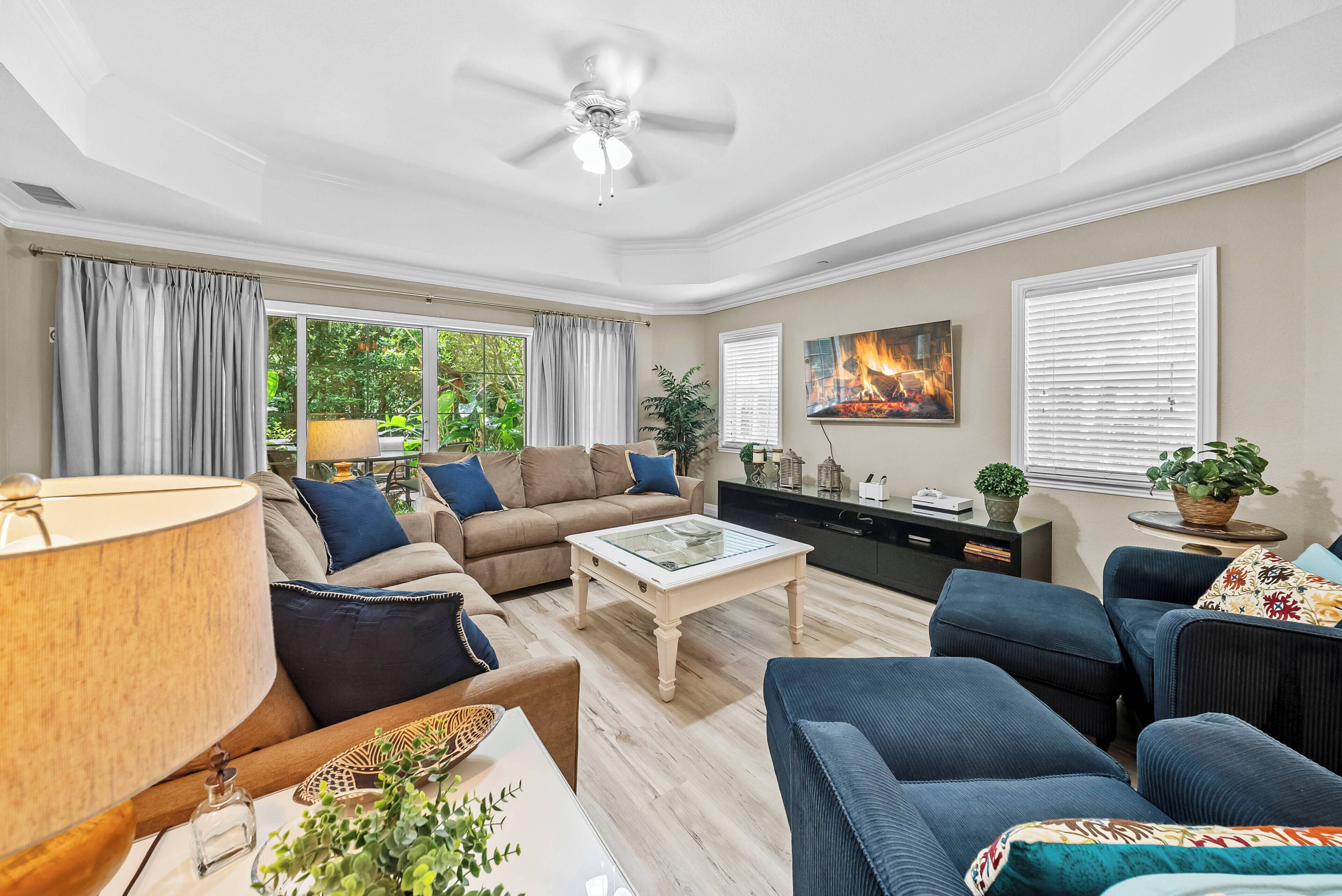 A living room with a ceiling fan, a fireplace, and a large window with curtains.