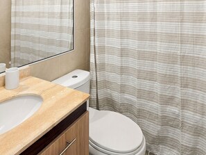 A bathroom with a toilet, sink, and a shower curtain. - Oceana Suites Centro Carrera (Temuco)