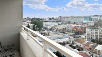 A balcony with a view of a cityscape, including buildings and a clear sky.