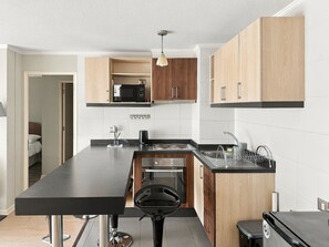 Una cocina compacta con una isla central, un microondas y un lavabo.