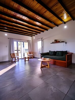 Un vaste espace de vie doté d’un plafond en bois, d’un canapé vert, d’une table en bois et d’une chaise.