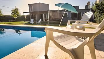 Une piscine avec des chaises longues et une maison en arrière-plan.
