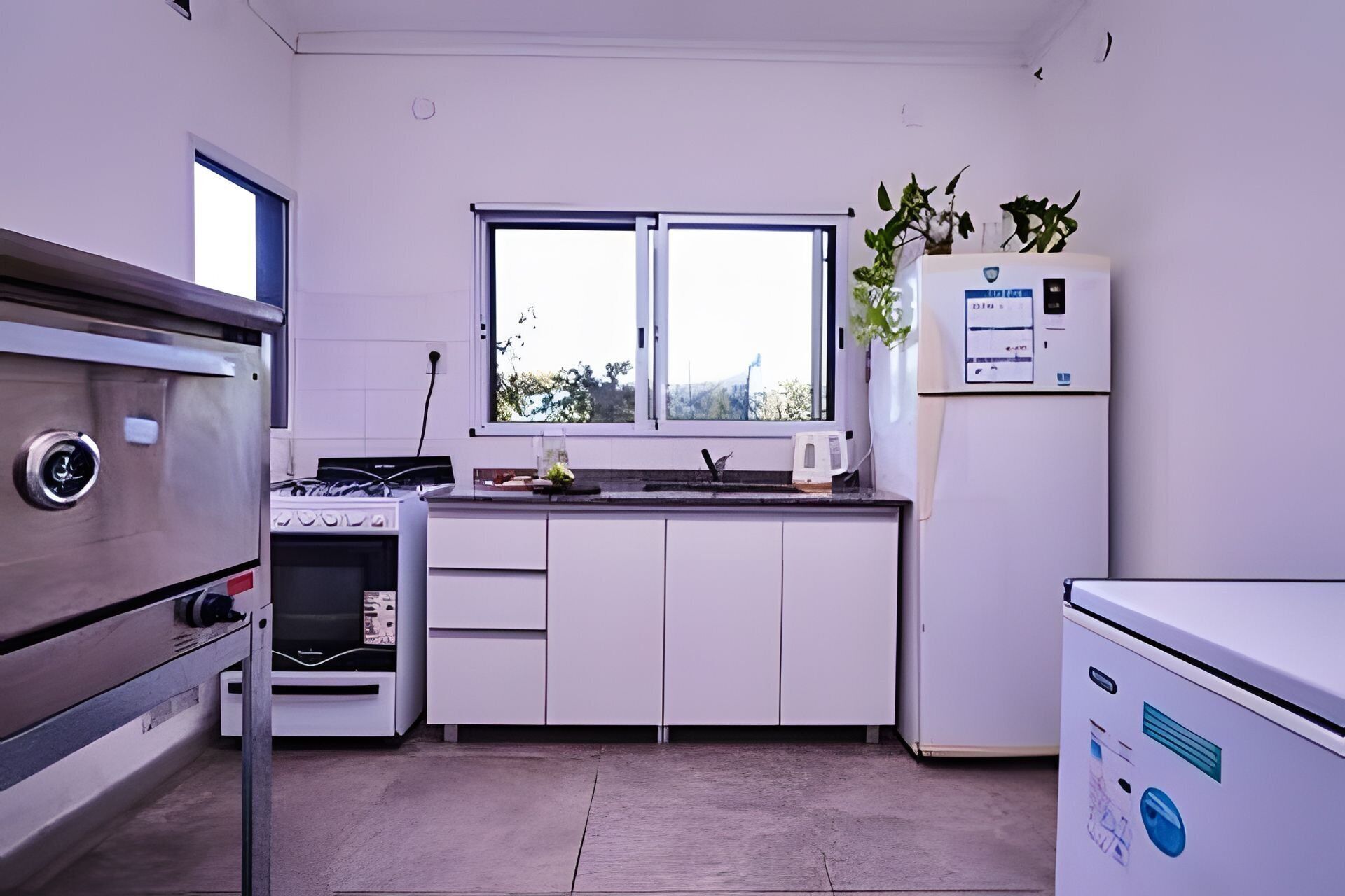 Une cuisine de taille réduite, avec des meubles blancs, une cuisinière, un évier et un réfrigérateur.