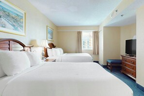 Une chambre d’hôtel avec deux lits, une télévision, une commode et une fenêtre avec des rideaux.