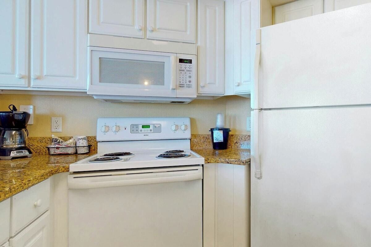 A kitchen with white cabinets, a microwave, a stove, and a refrigerator.