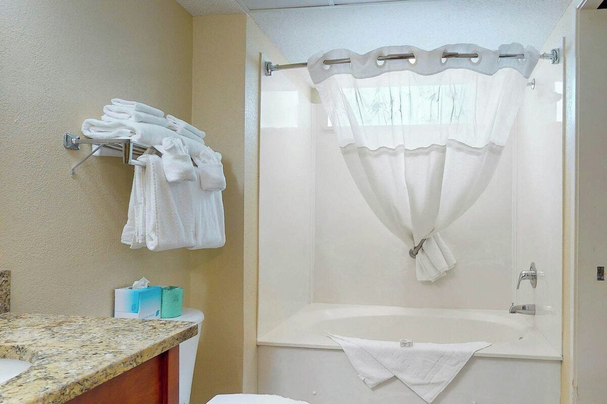 Une salle de bain avec un rideau de douche, un porte-serviettes avec des serviettes, une baignoire et des toilettes.