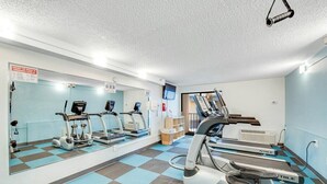 Un gimnasio con cintas de correr, elípticas y un espejo grande.