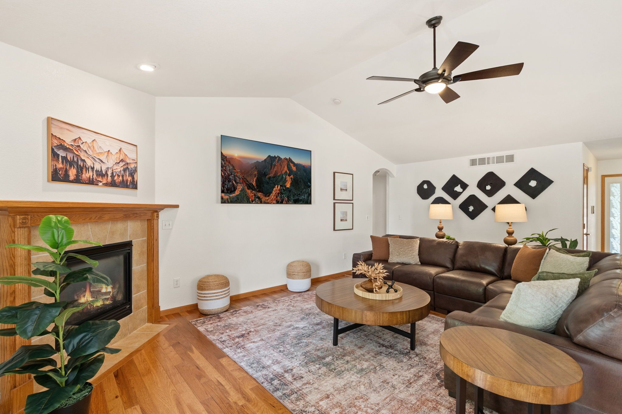 A living room with a fireplace, a sofa set, a coffee table, and a ceiling fan.