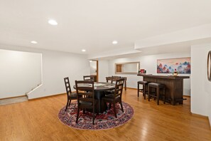A dining area with a round table, chairs, a wooden bar, and a painting on the wall. - The Gathering Place 6BR Retreat With Game Room (Loveland)