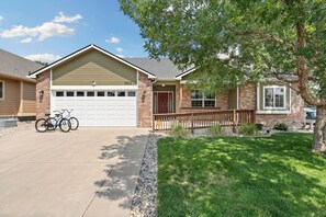 A residential house with a garage, a driveway, and a well-maintained lawn. - The Gathering Place 6BR Retreat With Game Room (Loveland)