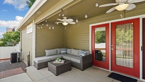 An outdoor seating area with a sectional sofa, a coffee table, and a ceiling fan.