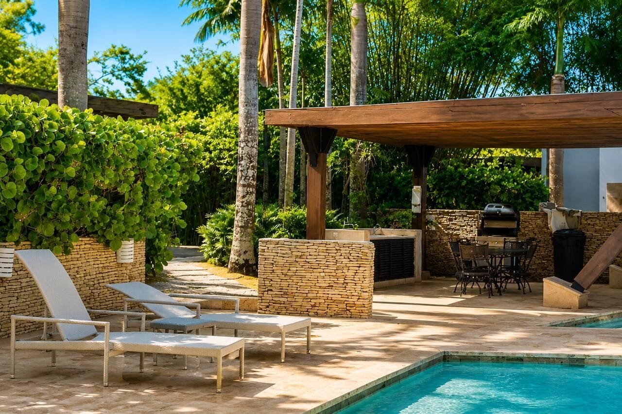A poolside area with lounge chairs, a barbecue grill, and a stone wall.