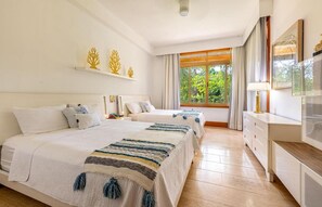Ein Hotelzimmer mit zwei Betten, einem Schreibtisch, einem Fernseher und einem Fenster mit Vorhängen.