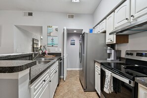 A modern kitchen with granite countertops, stainless steel appliances, and white cabinetry. - Ground floor 2 Bedroom One Bathroom Condo in gated community with Pool (Seminole)