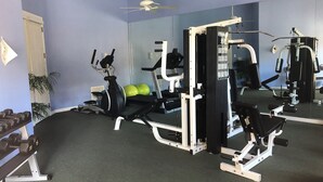 Une salle de sport équipée de matériel d’exercice, d’un tapis de course et de ballons d’exercice verts.
