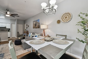 A dining area with a table set for four, a ceiling fan, and a kitchen in the background. - Ground floor 2 Bedroom One Bathroom Condo in gated community with Pool (Seminole)