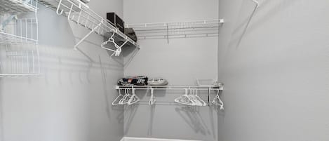 A corner closet with white metal shelving, a wooden floor, and a grey wall.