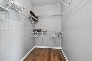 A corner closet with white metal shelving, a wooden floor, and a grey wall. - Ground floor 2 Bedroom One Bathroom Condo in gated community with Pool (Seminole)