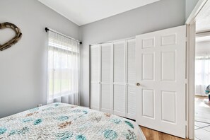 Un dormitorio con cama, armario y ventana con cortinas.