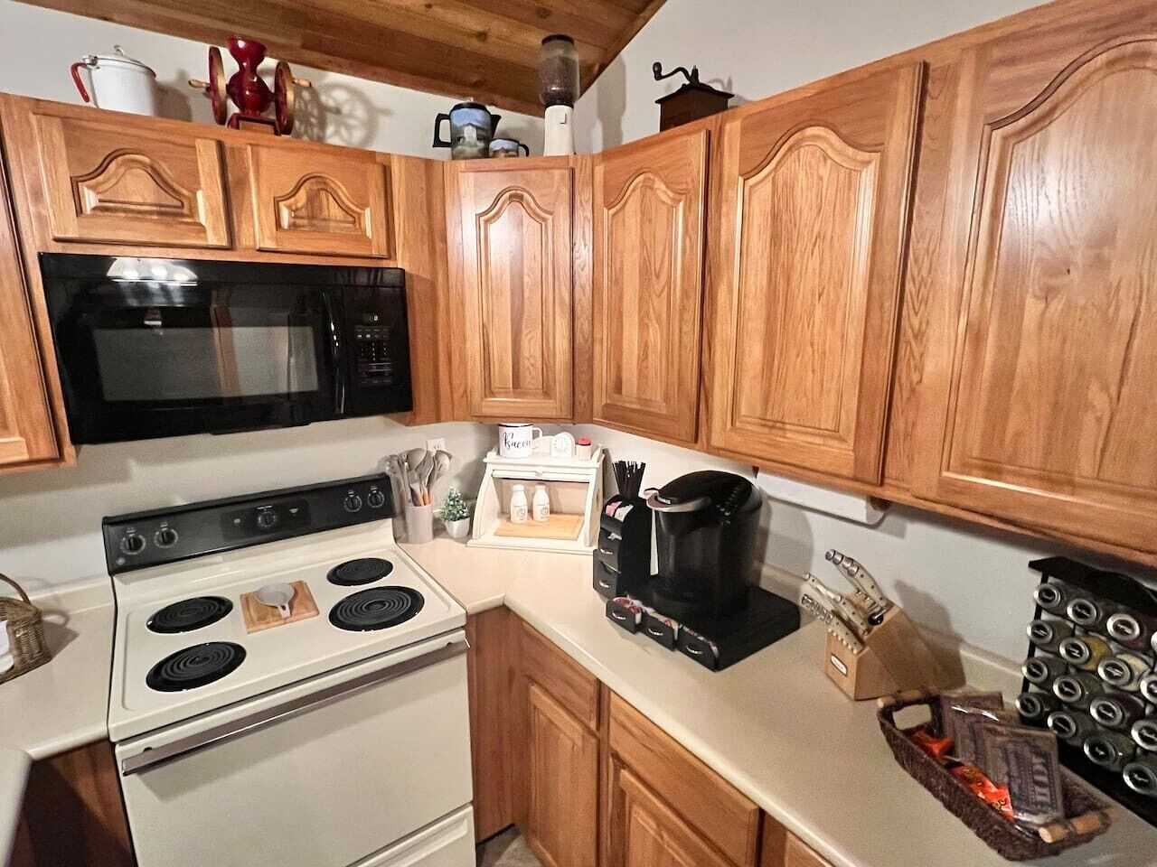 Una cocina con armarios de madera, estufa, horno, cafetera y especias.