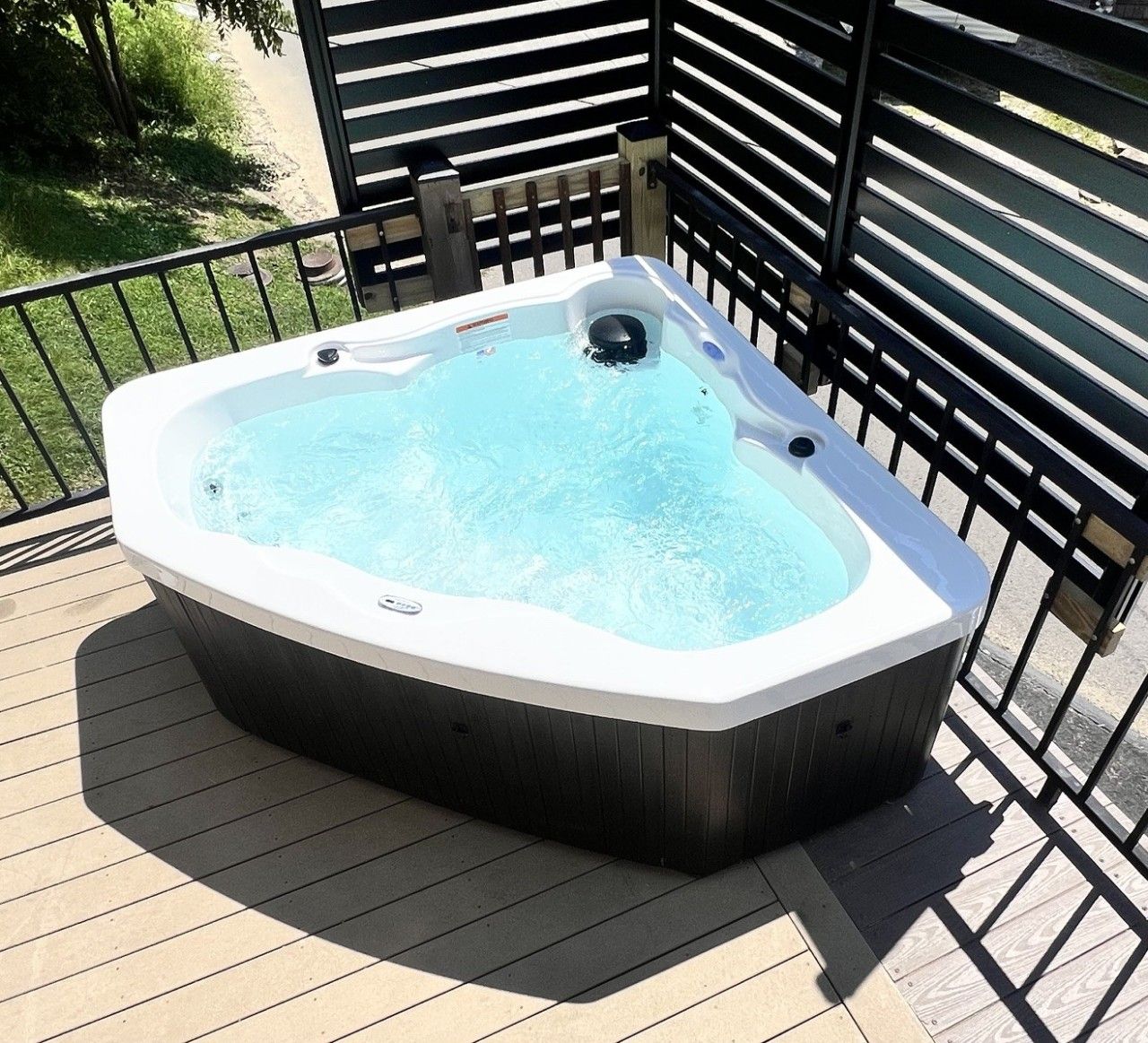 A hot tub on a wooden deck with a metal railing.