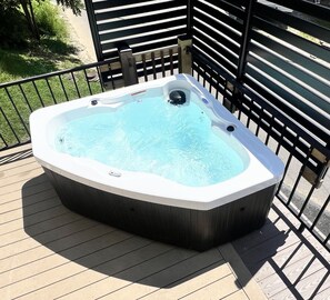 A hot tub on a wooden deck with a metal railing.