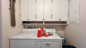 A laundry area with a washing machine, a dryer, and a cabinet with cleaning supplies.